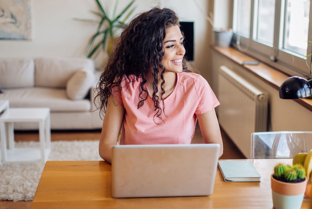 Frau sitzt am Laptop und blickt zur Seite