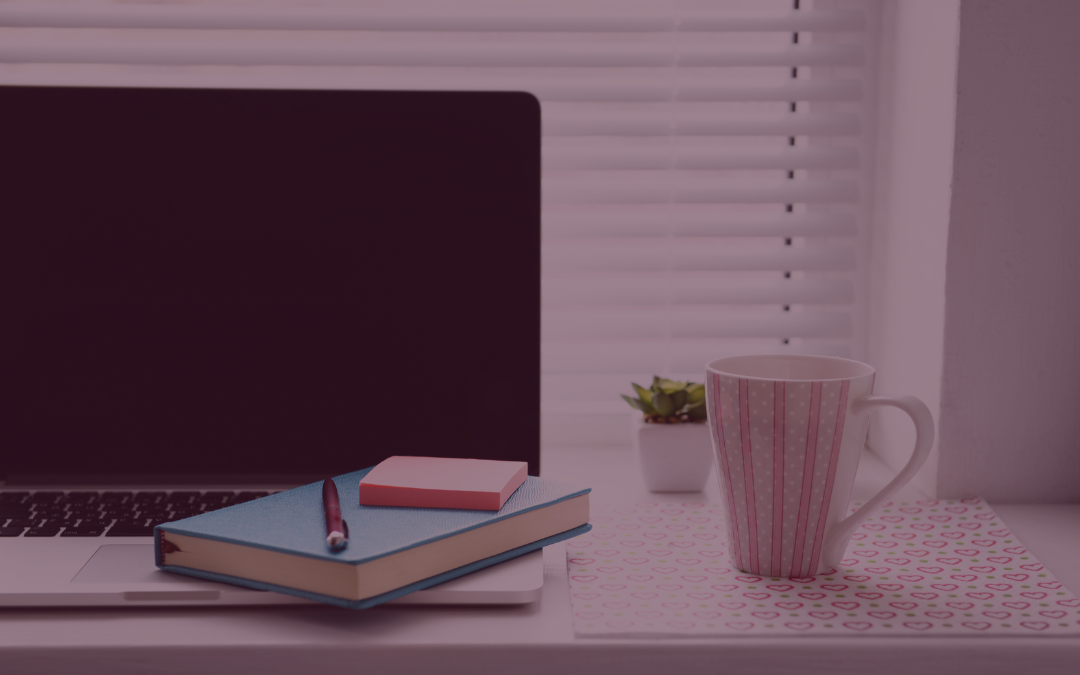Laptop auf einem Schreibtisch mit einem Notizbuch und einer Tasse